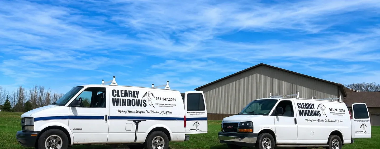 Two wrapped Clearly Windows service vans parked outside the shop